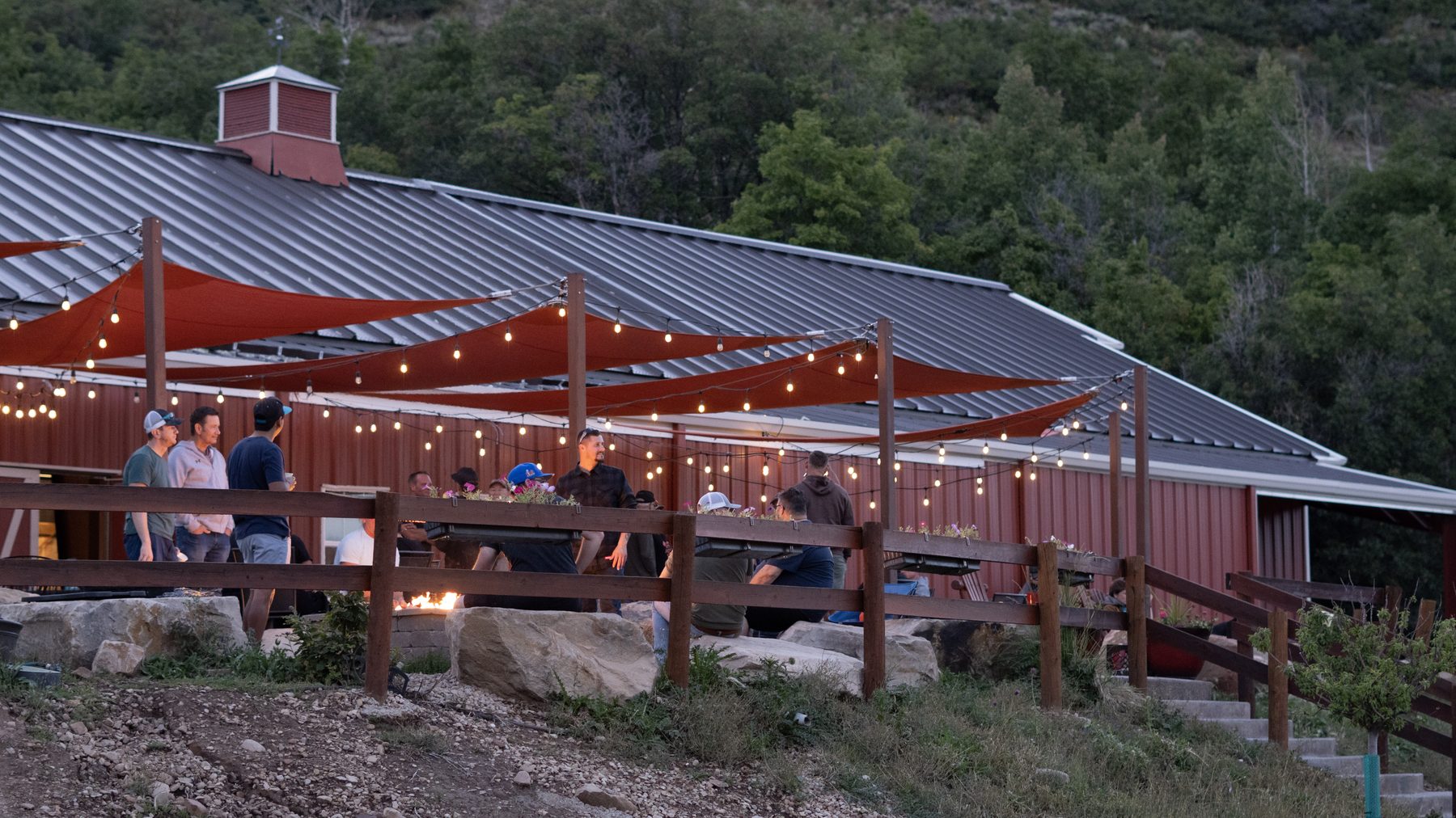 Men gathered under string lights at Big Canyon Ranch at dusk